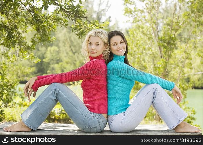 Side profile of two young women sitting back to back