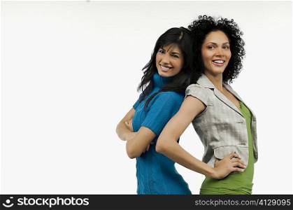 Side profile of two young women standing back to back and smiling