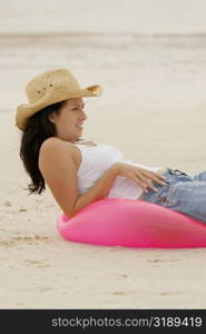 Side profile of young woman lying on an inflatable ring at the beach