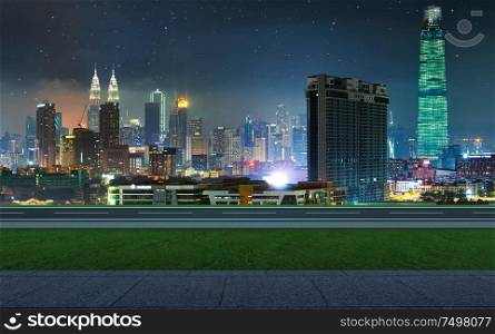 Side view asphalt road with walkway and green grass on night , Kuala Lumpur city .