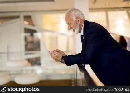 Side view at senior businessman using mobile phone in the office