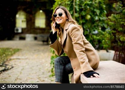 Side view at young woman sitting outdoor and using mobile phone