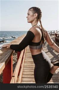 side view athletic woman stretching by beach 2