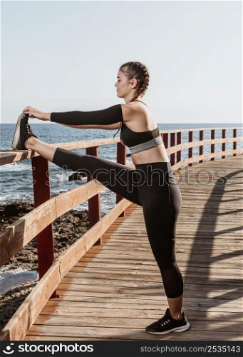 side view athletic woman stretching outdoors by beach