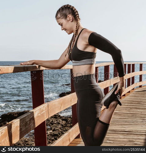 side view athletic woman stretching outside by beach