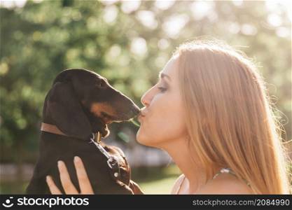 side view beautiful young woman kissing her dog
