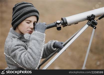 side view boy using telescope