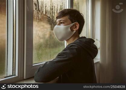 side view boy with face mask looking through window