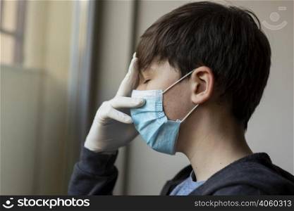 side view boy with medical mask touching his face