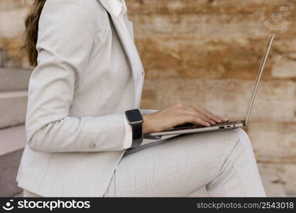 side view businesswoman with smartwatch working laptop outdoors