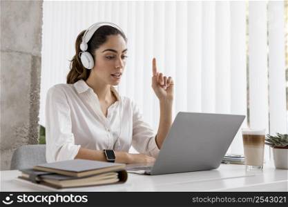 side view businesswoman working with headphones laptop