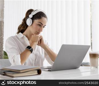 side view businesswoman working with laptop headphones