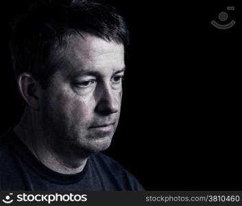 Side view close up of mature man showing negative emotions with dark background