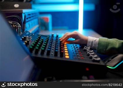 Side view closeup audio engineer hand on sound mixer control panel inside production house. Closeup audio engineer hand on sound mixer control panel