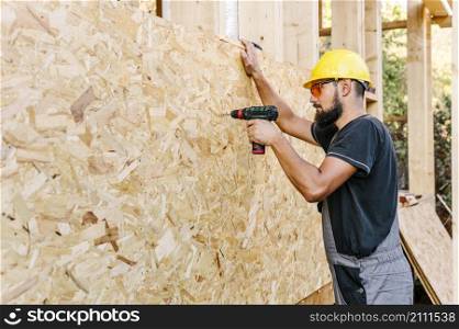 side view construction worker drilling plywood with copy space