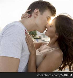 side view couple kissing with sun peeking them