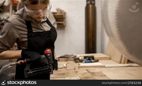 side view female carpenter with pneumatic stapler