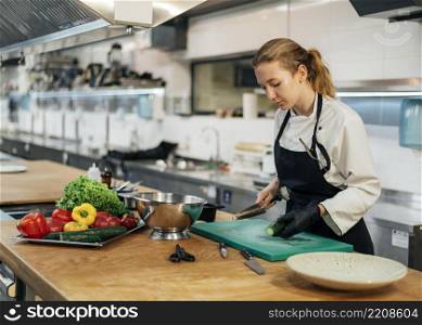 side view female chef kitchen slicing vegetables