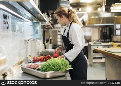 side view female chef washing vegetables kitchen