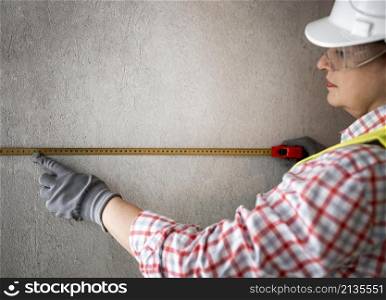 side view female construction worker with helmet tape measurer