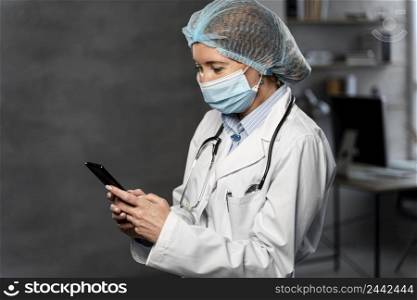 side view female doctor with medical mask hairnet holding smartphone