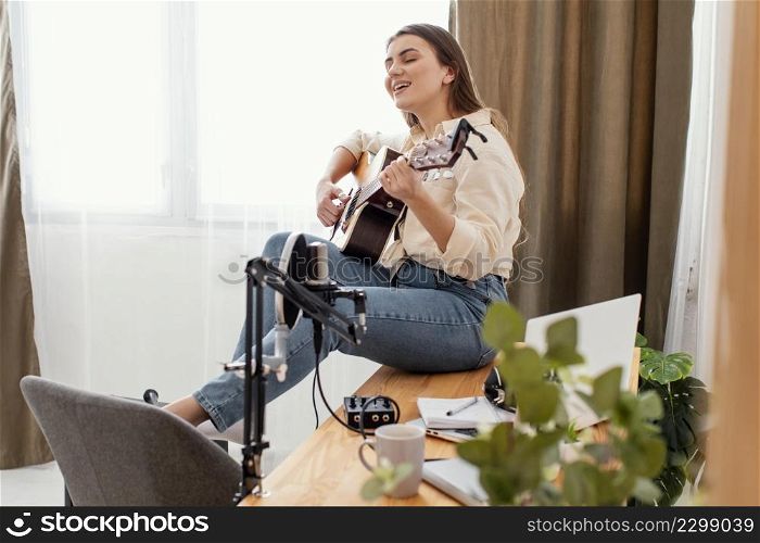 side view female musician home playing acoustic guitar singing