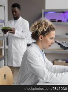 side view female researcher laboratory with microscope male colleague
