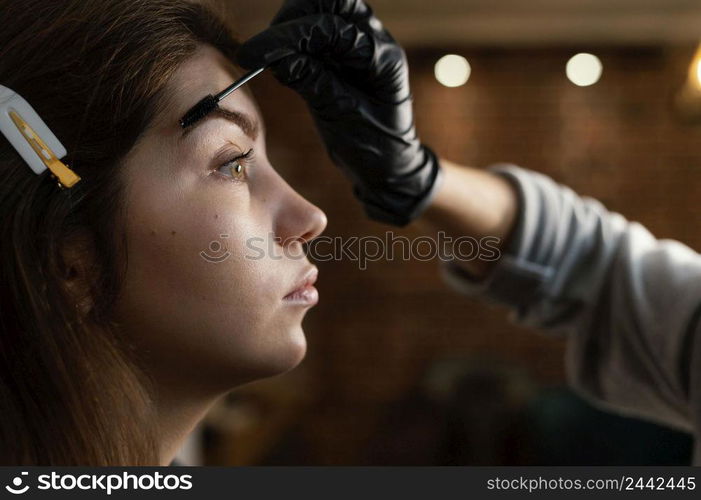 side view female specialist doing eyebrow treatment woman