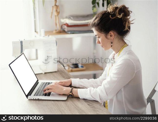side view female tailor using laptop