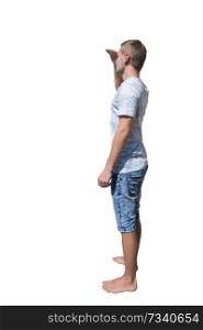 Side view full length portrait of casual young man holding hand to forehead over eyes to protect from sun rays, searching or looking for someone isolated over white background.