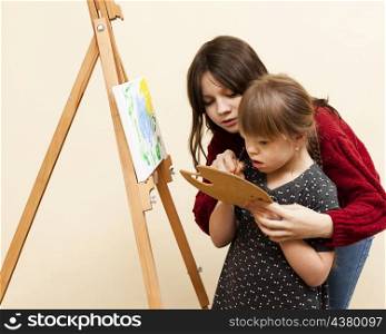 side view girl helping girl with down syndrome paint