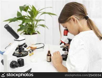 side view girl looking into microscope