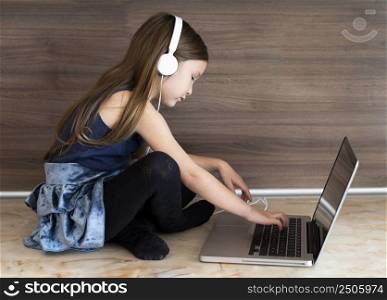 side view girl using laptop with headphones