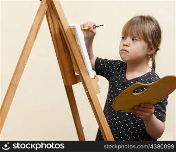 side view girl with down syndrome painting with easel