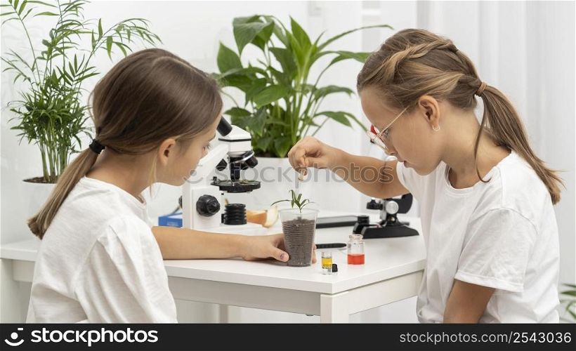 side view girls learning about science with plant