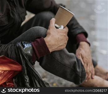 side view homeless man holding cup