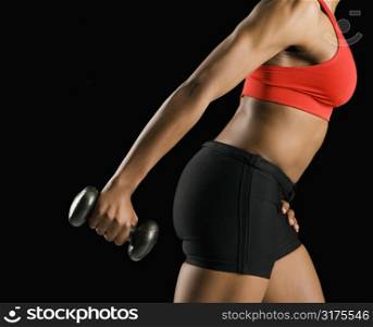 Side view if torso of African American young adult woman holding dumbbell outstretched.