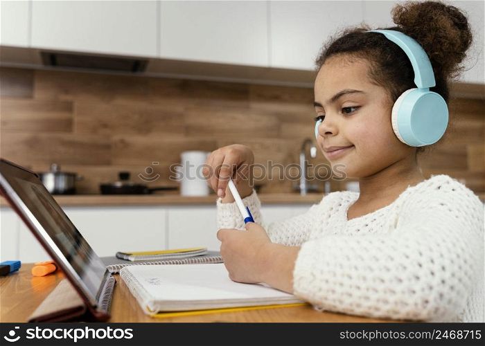 side view little girl during online school with tablet headphones