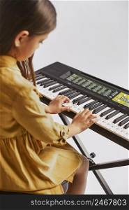 side view little girl learning how play electronic keyboard