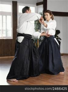 side view male martial arts instructor training with female trainee practice hall