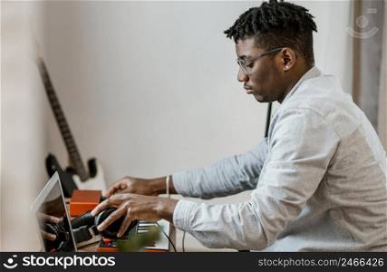 side view male musician home mixing music with laptop
