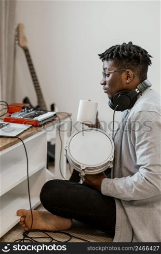 side view male musician home playing drums mixing with laptop