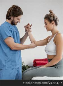 side view male osteopathic therapist checking female patient s elbow