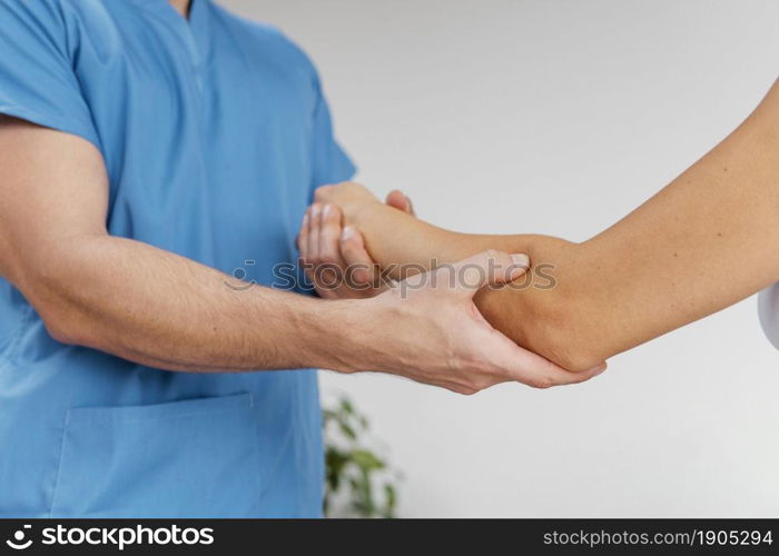 side view male osteopathic therapist checking female patient s elbow joint movement. Beautiful photo. side view male osteopathic therapist checking female patient s elbow joint movement