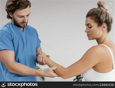 side view male osteopathic therapist checking female patient s elbow movement