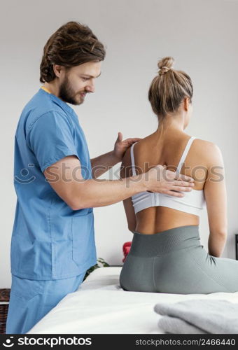 side view male osteopathic therapist checking female patient s scapula