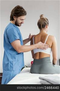 side view male osteopathic therapist checking female patient s scapula