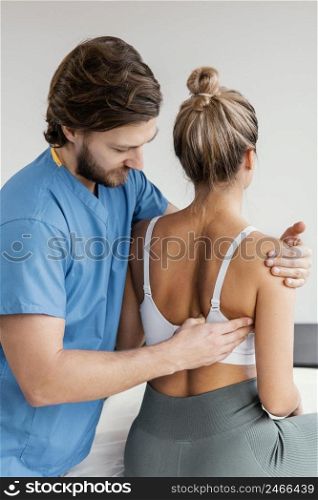 side view male osteopathic therapist checking female patient s scapula movement