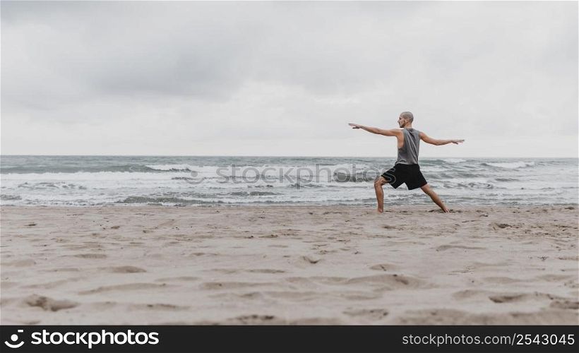 side view man beach exercising yoga with copy space