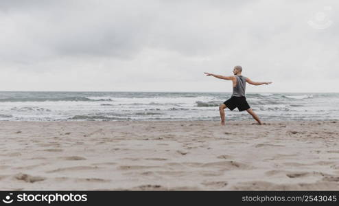side view man beach exercising yoga with copy space